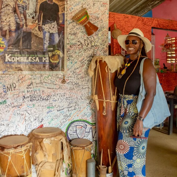A person standing next to a wall covered with signatures and a poster of a band. 4
