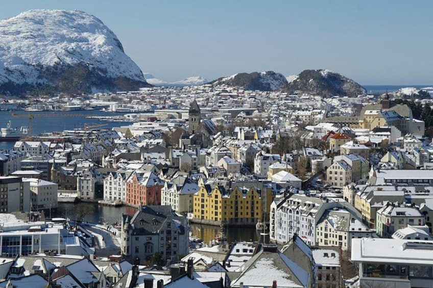 A snow-covered cityscape with historic buildings and a large mountain in the background. 5