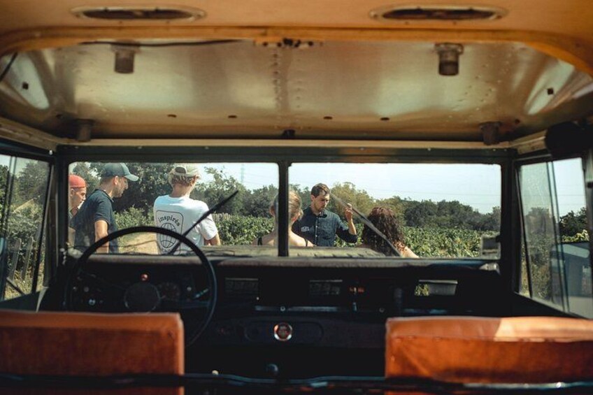 The interior of a vehicle with a steering wheel, dashboard, and a view of the outside through the windshield. 2