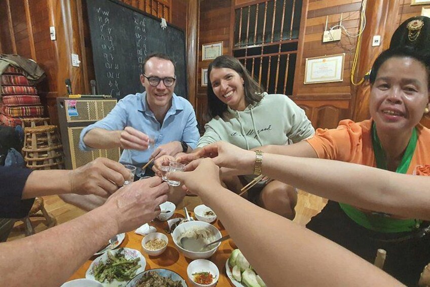 A group of people sitting around a table with food, engaged in a meal. 5