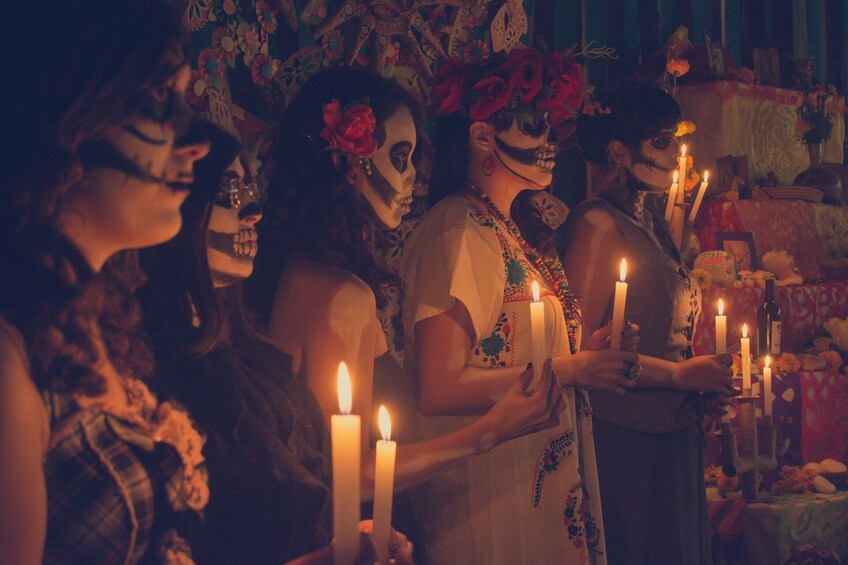 People with face paint and candles in a dimly lit room. 5