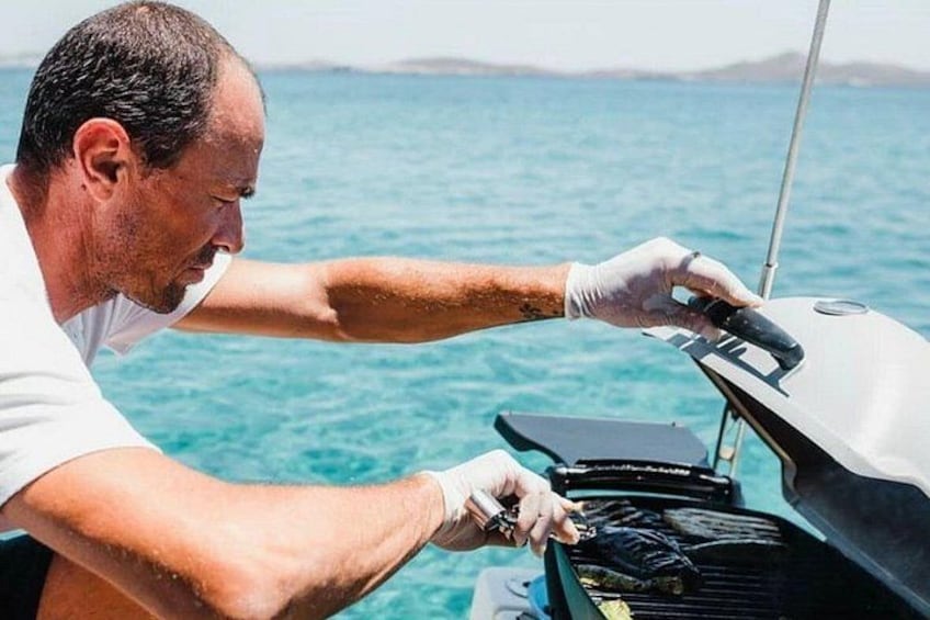 Una persona asando en un barco, con vista despejada al océano y la costa distante. 1