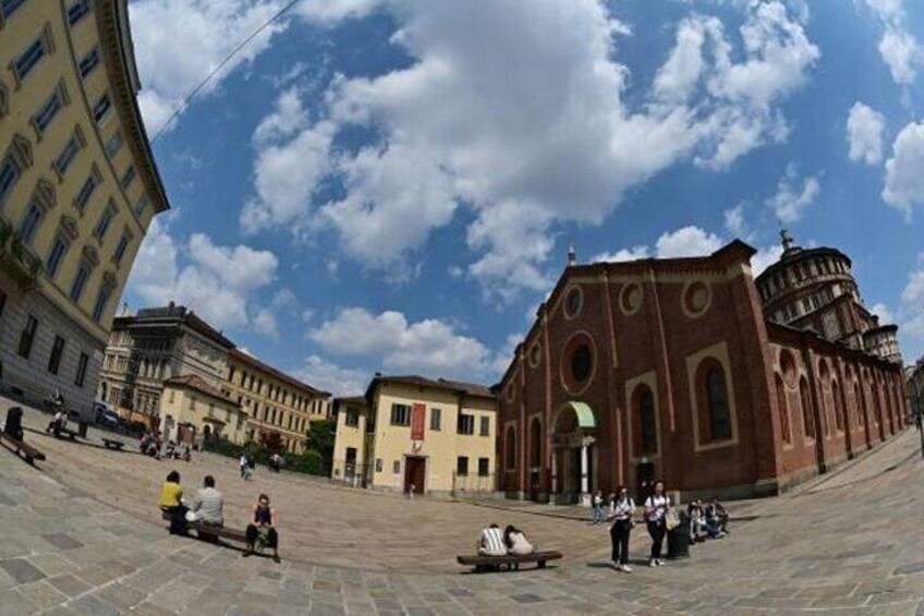 A public square with a prominent red-brick building, a fountain, and surrounding historic architecture. 5