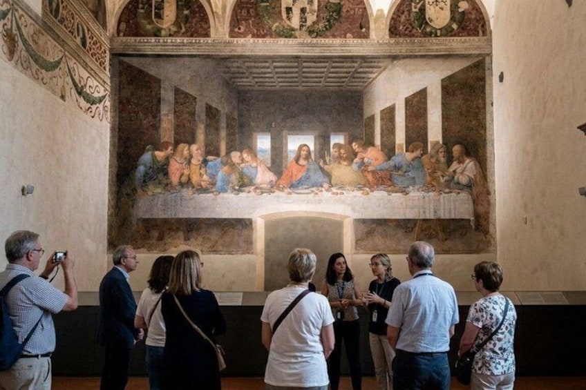 A group of people observing a famous painting in a historic building. 1