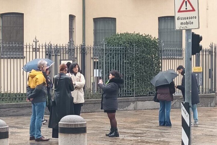 A group of people standing on a street corner, some holding umbrellas. 4