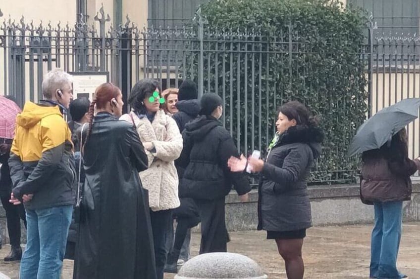 A group of people standing outdoors, some holding umbrellas. 3