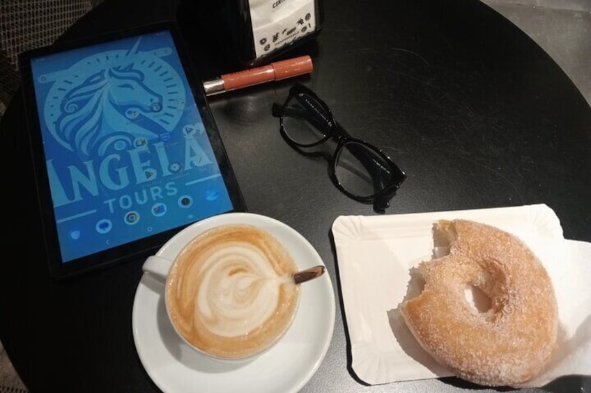 A tablet displaying 'INGELA TOURS' with a coffee cup and a sugar-coated donut on a table. 2