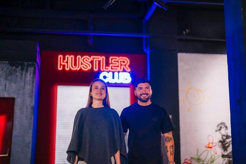 Deux personnes se tiennent devant une enseigne au néon sur laquelle on peut lire « HUSTLER CLUB ». 5