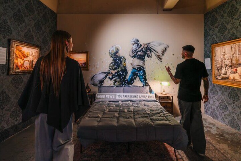 Une chambre à coucher avec un lit, une fresque murale et des tableaux encadrés accrochés au mur. 2