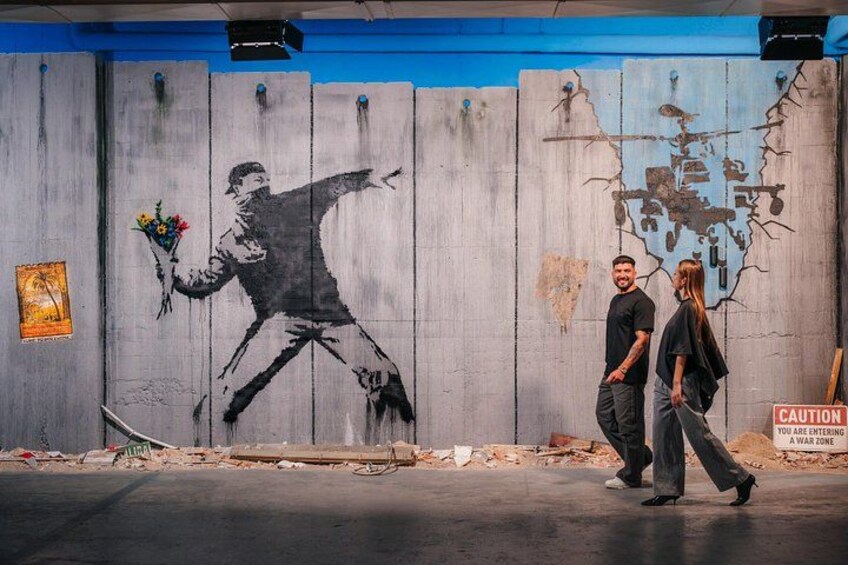 A mural of a man dancing on a wall, a caution sign, and a poster. 2