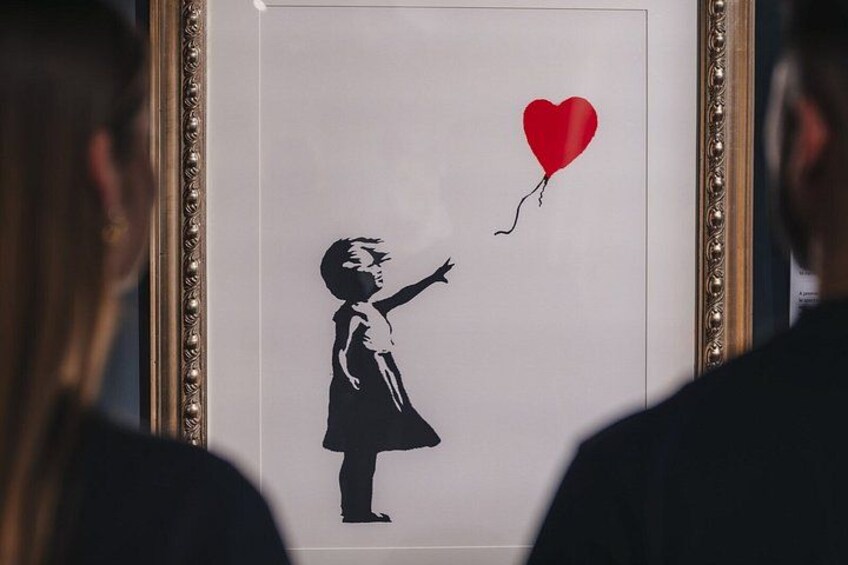 A framed artwork of a girl reaching for a red heart-shaped balloon. 1