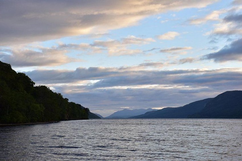 A calm lake with mountains in the background and a cloudy sky. 3