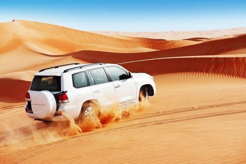 A white SUV driving through a desert with sand dunes. 3