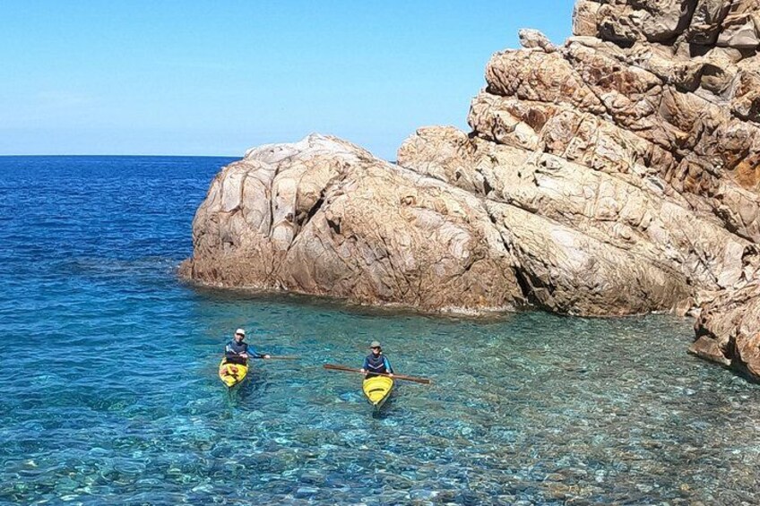 Two people kayaking near a rocky coastline. 3