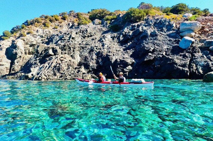 A kayak on clear turquoise water with rocky cliffs in the background. 2