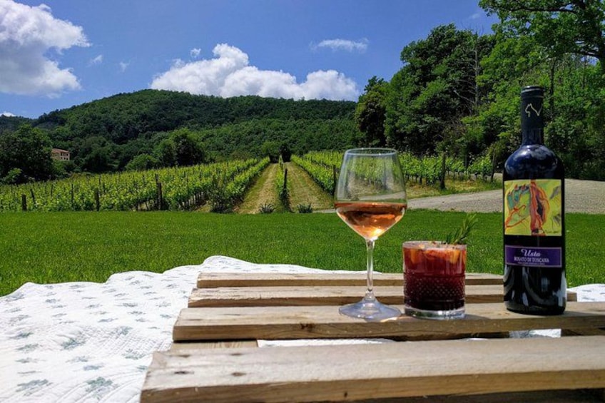 Un viñedo, una botella de vino y una copa de vino sobre una mesa de madera. 1