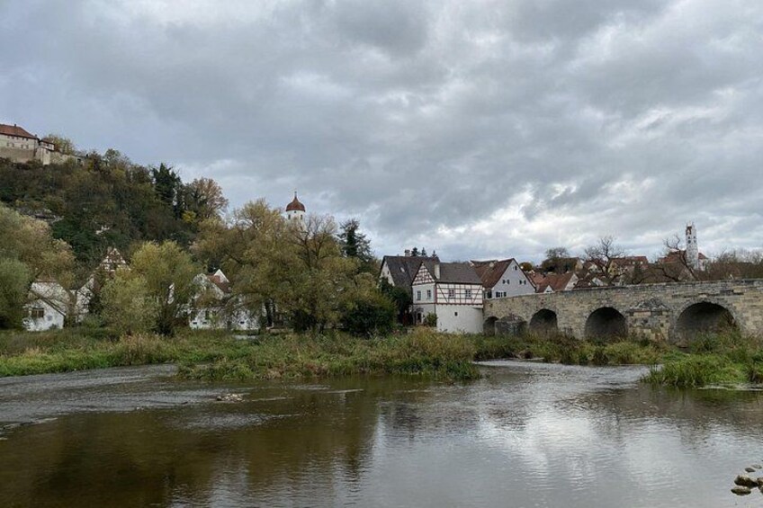 A river with a stone bridge, houses, and a hilltop building. 2