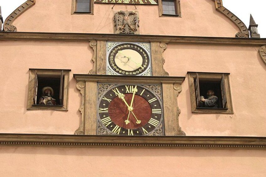 A building with a large clock and two small windows with statues. 4