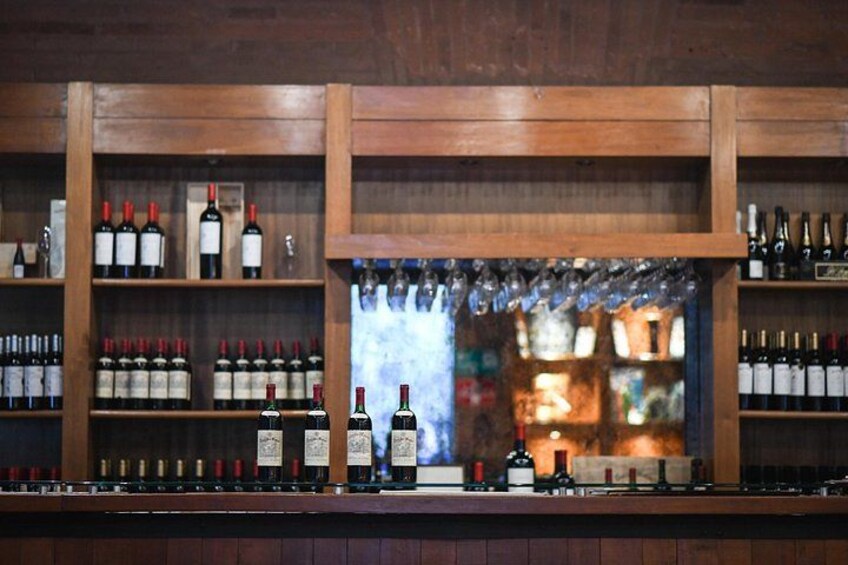 A bar with wooden shelves stocked with bottles and glasses. 4