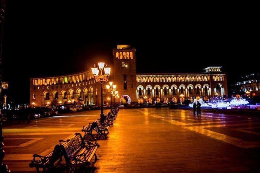 A historic building with arches and a tower, illuminated at night. 1