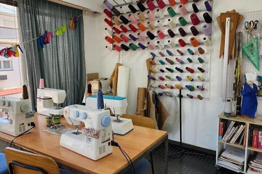 A sewing room with multiple sewing machines, a pegboard with spools of thread, and various sewing supplies. 5