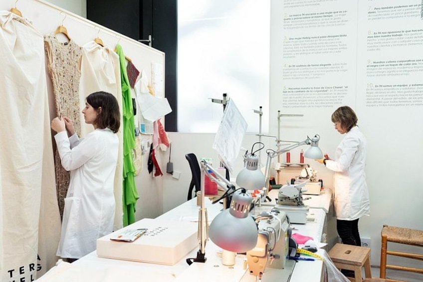 Two individuals in a lab setting, one working on a fabric and the other using a sewing machine. 1