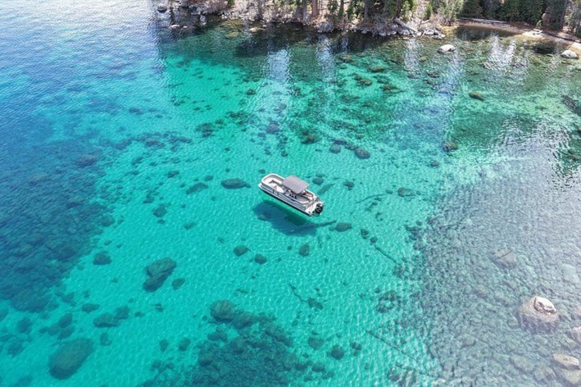 Una embarcación en aguas turquesas cristalinas con rocas visibles y una costa rocosa. 1