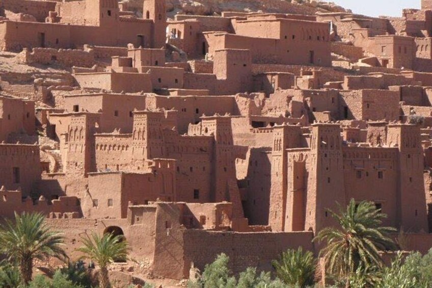 A dense cluster of traditional adobe buildings with flat roofs and small towers, surrounded by sparse vegetation. 2