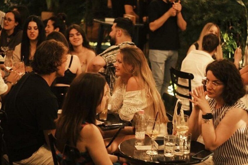Un gruppo di persone sedute a un tavolo all'aperto, con bevande e bicchieri. 2