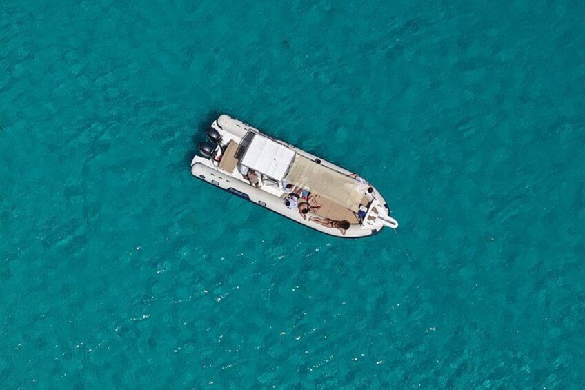 Un petit bateau doté d’une cabine et de chaises longues, naviguant sur une eau turquoise. 3