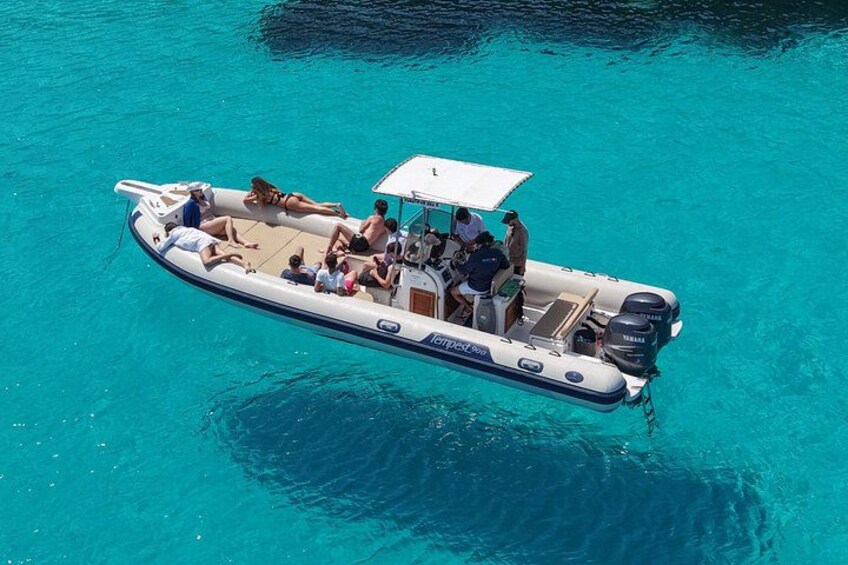 Un petit bateau pneumatique avec des personnes à bord, flottant sur une eau turquoise et limpide. 4