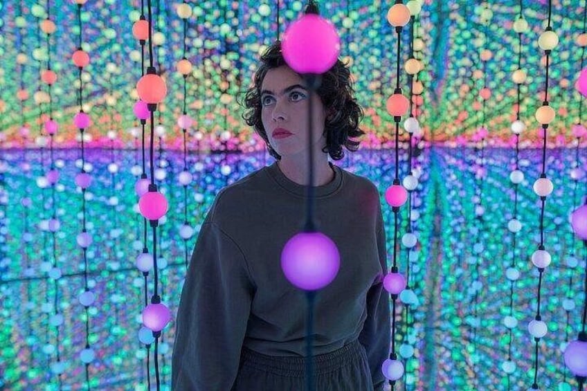 A person standing in front of a wall with hanging spherical lights. 5