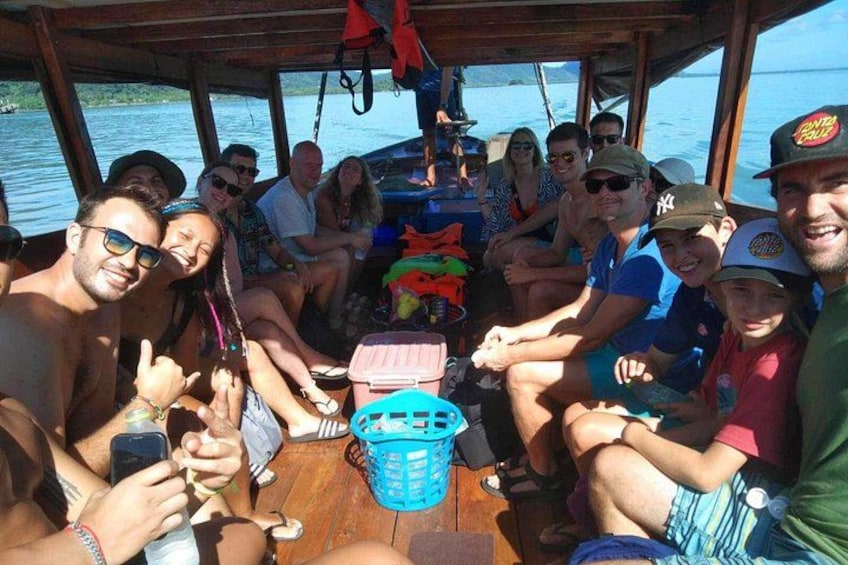 A group of people on a boat with a blue basket and a pink cooler. 2