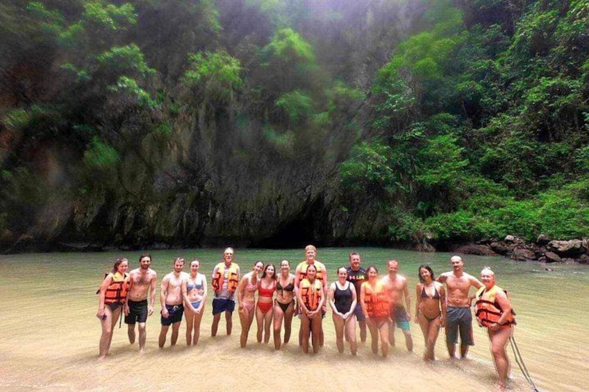 A group of people in swimsuits on a sandy beach with a forested backdrop. 4