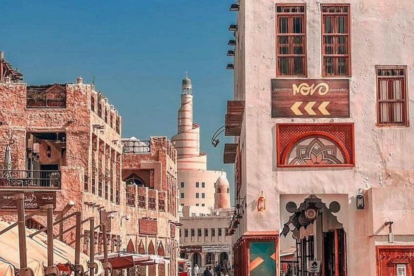 A historic street with traditional architecture, including a minaret and ornate doorways. 5
