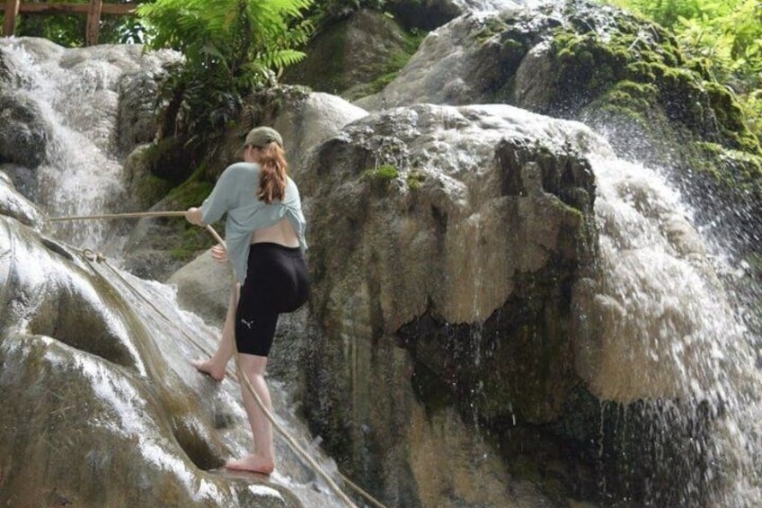 A person standing on a rock by a waterfall. 4