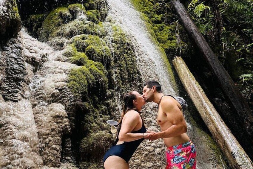 A couple kissing in front of a moss-covered waterfall. 3