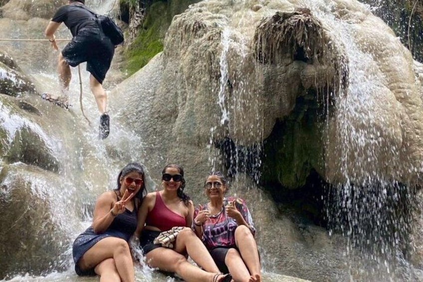 Three people sitting by a waterfall in a natural setting. 2