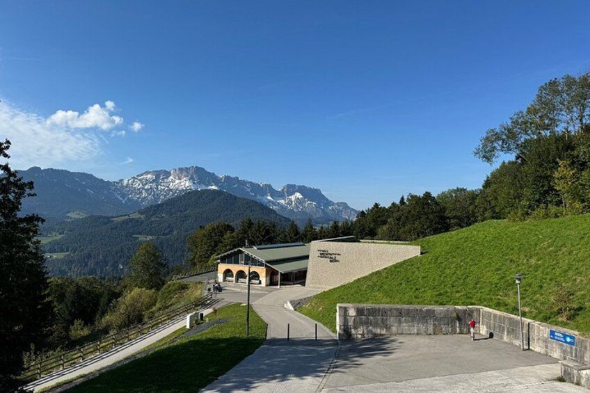 Ein Gebäude mit einem geneigten Dach, einem gepflasterten Weg und Blick auf Berge im Hintergrund. 4