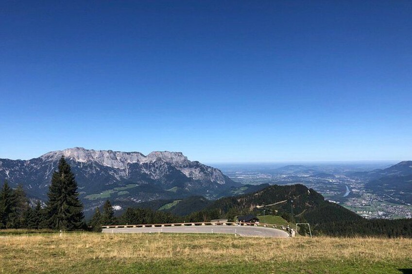 Eine Berglandschaft mit blauem Himmel, einer Straße und weiter Aussicht auf ein Tal. 5