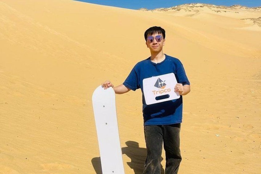 A person holding a snowboard in a desert landscape. 4