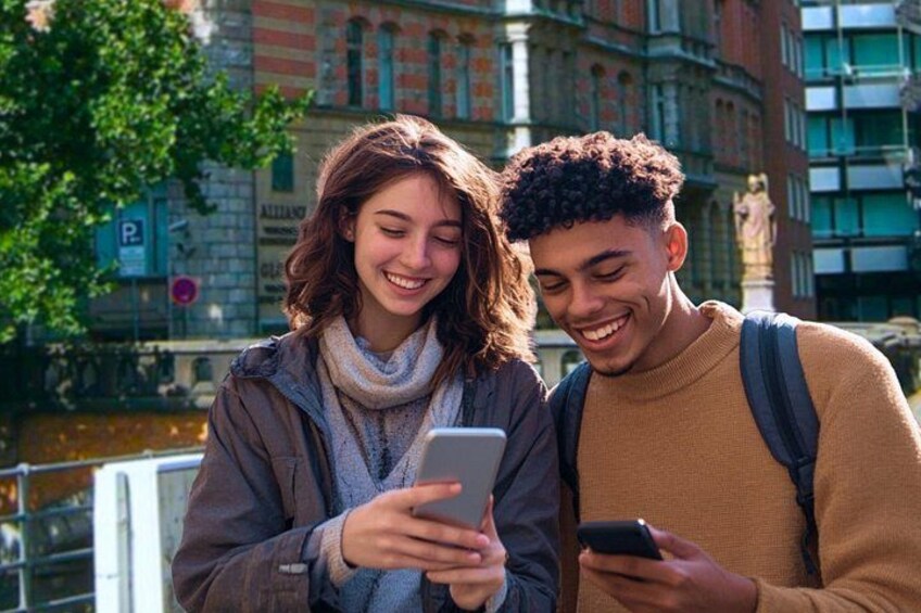 Two people standing outdoors, one holding a smartphone. 1