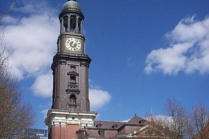 A clock tower with a dome and a clock face, surrounded by trees and a clear sky. 2