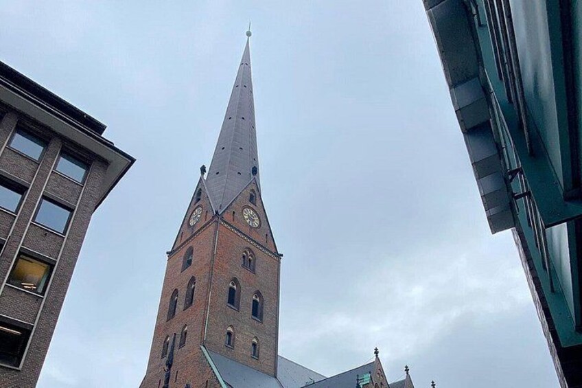A church tower with a pointed spire and clock faces. 3