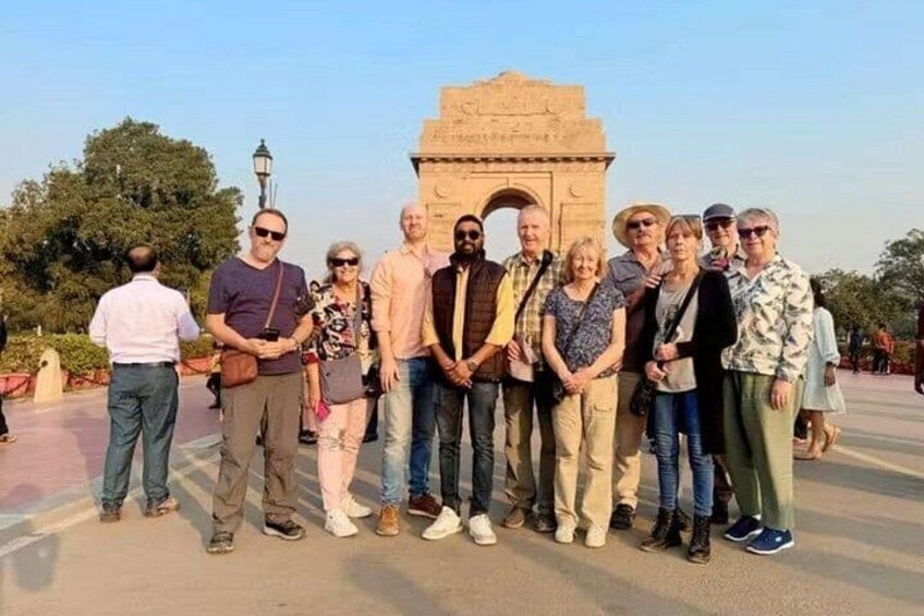 A group of people standing in front of a large stone archway. 5