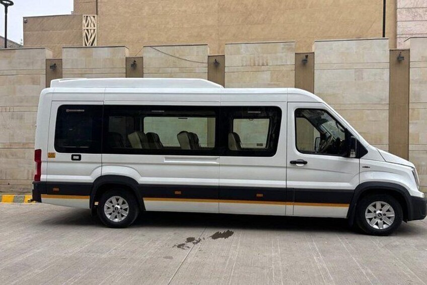 A white van parked in front of a beige building with a black and yellow stripe. 4