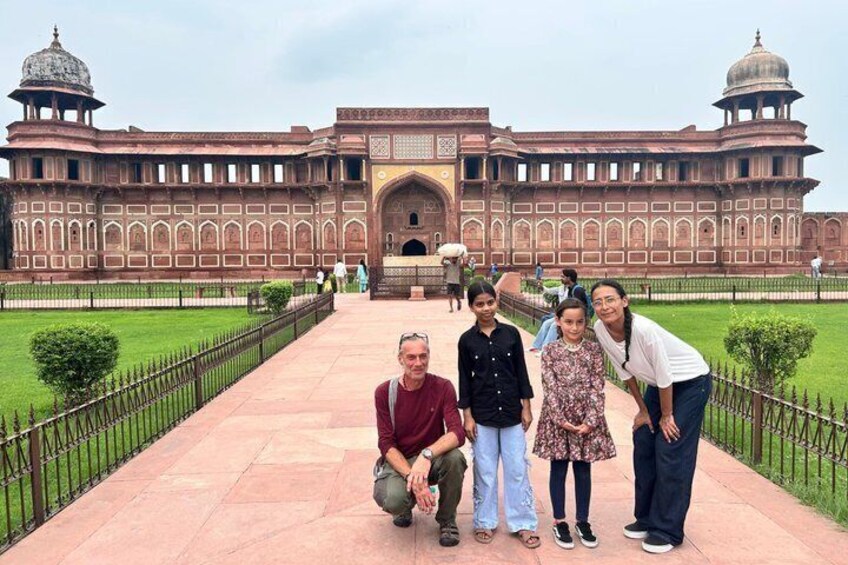 A group of people posing in front of a large, historic building with domes and arches. 2