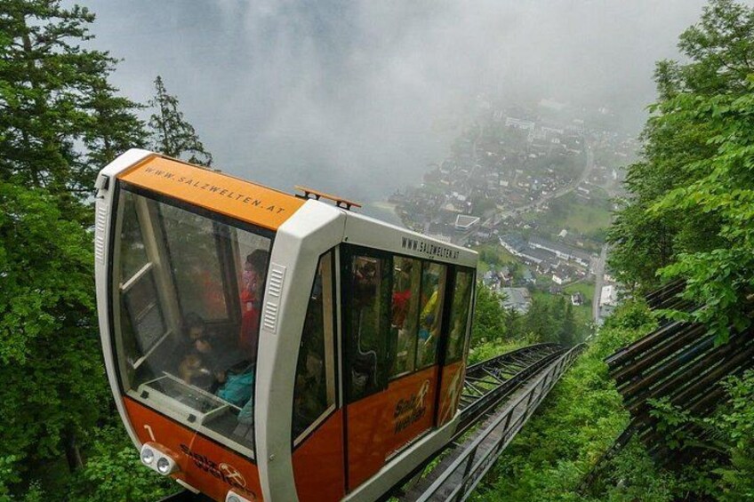 A cable car moving along a track surrounded by lush greenery. 5