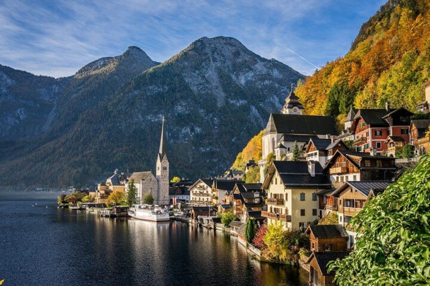 A lakeside village with a church, houses, and mountains in the background. 1