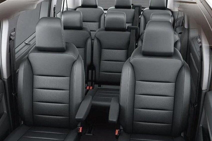 A vehicle's rear seating area with black leather seats and a center console. 4